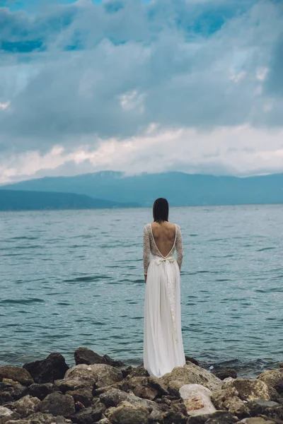 Beautiful Bride standing by the Sea. Destination wedding concept. Wedding on exotic island. Bride in white wedding dress watching sea.