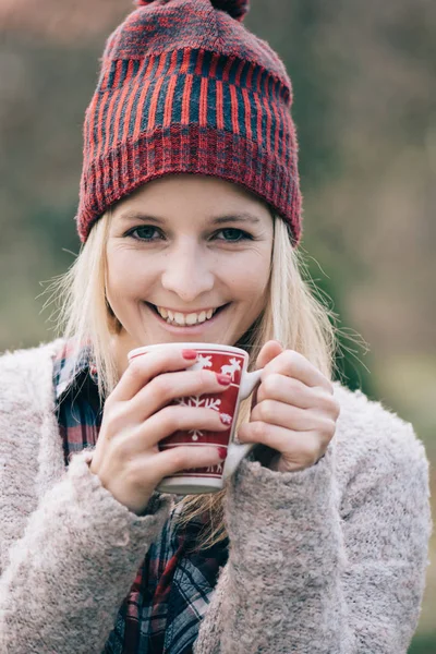 ホットド リンクを飲んでいる女性 赤い女の子の爪屋外でコーヒーや紅茶のカップを保持しています — ストック写真