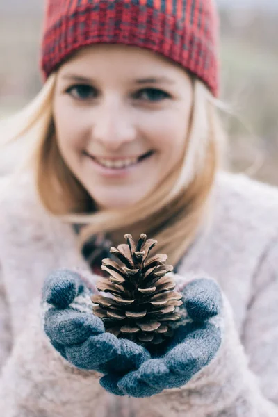 美しい女性の円錐形の松を屋外に保有します 冬の肖像画 前景に焦点を当てる — ストック写真