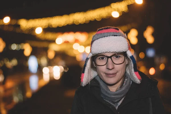 夜クリスマスの街の大気中で光背景照明の輝きボケ背中から黒いジャケットで内気な少女 背景のライト — ストック写真