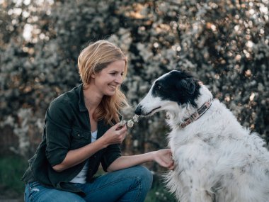 Köpekli bir kadın çiçeklerle oynuyor