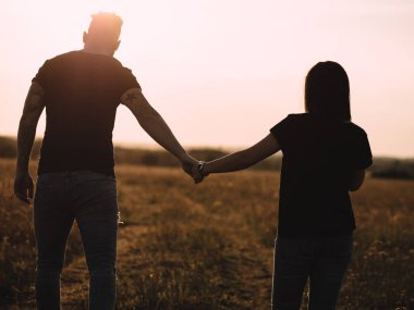  Gün batımında el ele tutuşan genç çift