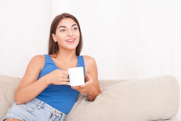 Kanepede oturan ve kahve içme genç esmer kadın — Stok fotoğraf