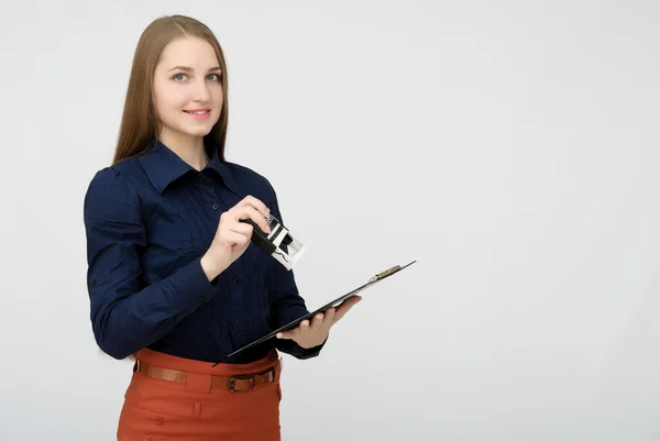 Portret van een lachende zakenvrouw met pen en papieren map. Jonge mooie arbeider schrijft iets in haar papieren. — Stockfoto