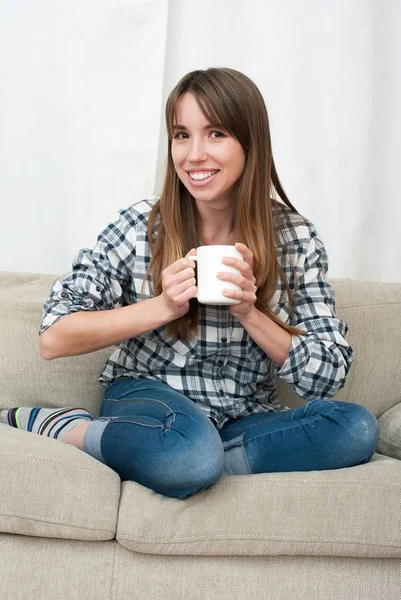 Mujer sentada en el sofá en su sala de estar y tomando café — Foto de Stock