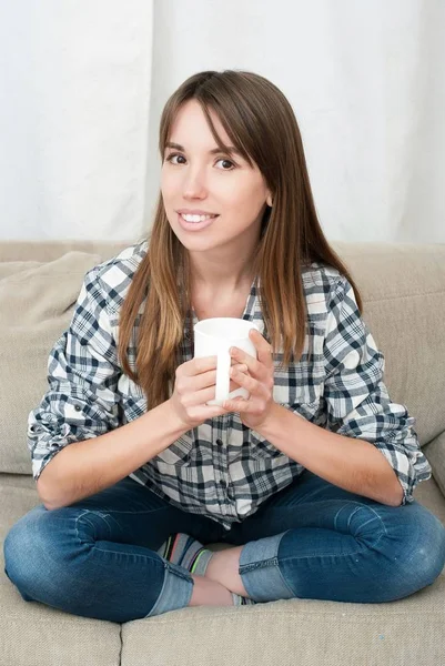 Mujer sentada en el sofá en su sala de estar y tomando café — Foto de Stock