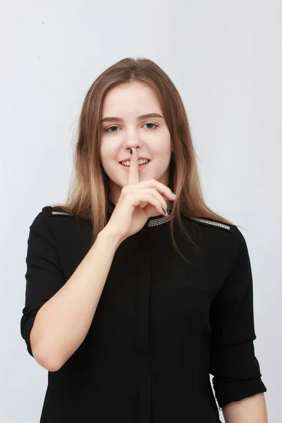 Piękna młoda dziewczyna trzyma palec w pobliżu usta na białym tle — Zdjęcie stockowe