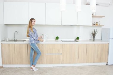 Genç güzel kız mutfakta kahve hazırlama ayakta ince. Bir kız holding su ısıtıcısı,