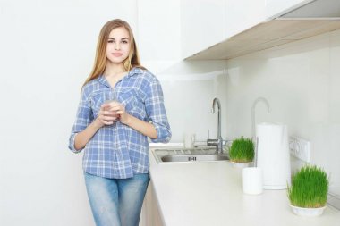 güzel bir genç kadın bir bardak su ile mutfak üzerinde tutar..