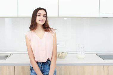 Ciddi tutum. Genç gülümseyen Bayan bir mutfakta ayakta.