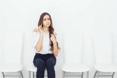 sandalyede oturan ve cep telefonuyla genç iş kadını