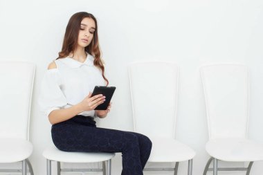 Genç kız bir sandalyede oturuyor ve tablet kullanma