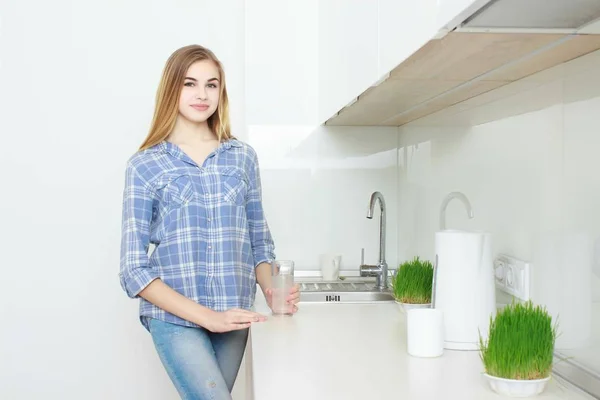 Красивая молодая женщина держит стакан с водой на кухне . — стоковое фото