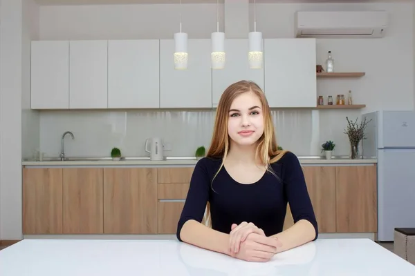 Junge Frau sitzt an einem Tisch in der Küche — Stockfoto