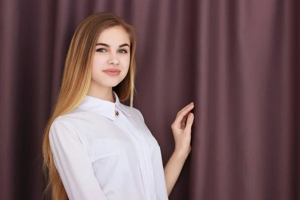 Oficina Chica en una blusa blanca contra un fondo de cortinas marrones — Foto de Stock