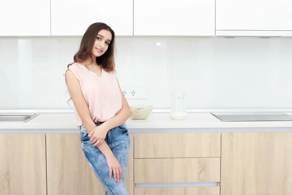 Atitude séria. Jovem sorridente senhora de pé em uma cozinha . — Fotografia de Stock