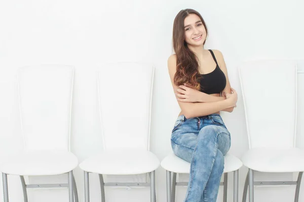Retrato de uma jovem encantadora posando na cadeira isolada em um fundo branco — Fotografia de Stock