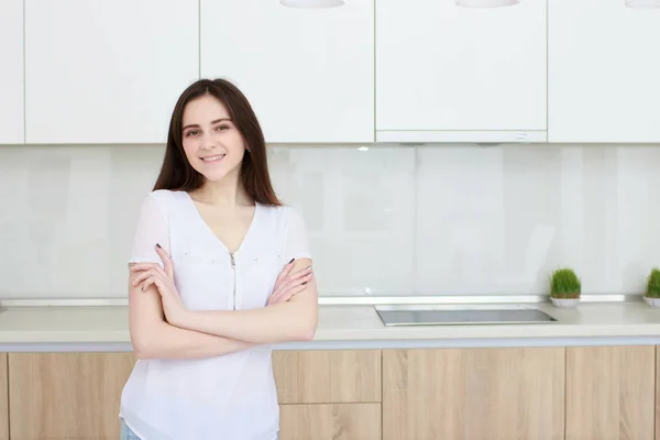 Mulher bonita com cabelo preto em pé na cozinha e sorrindo — Fotografia de Stock