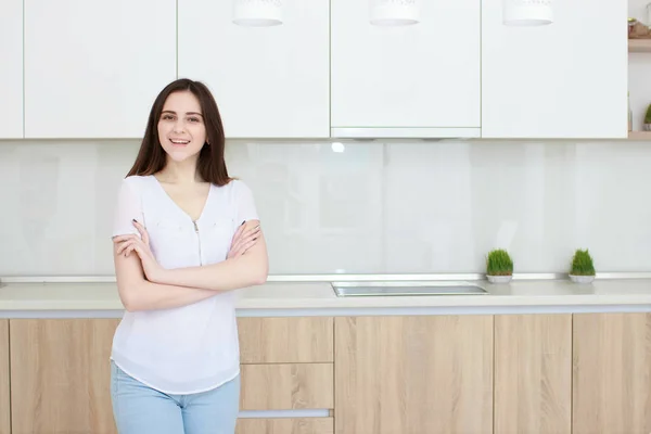 Красивая молодая женщина с черными волосами, стоящая на кухне и улыбающаяся — стоковое фото