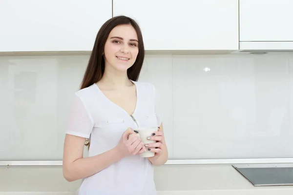 Junge Frau mit schwarzem Haar trinkt Kaffee in der Küche. — Stockfoto