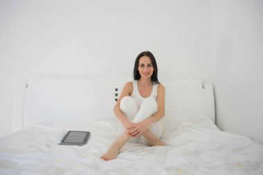 Bir kadın onun tablet kullanarak yatağında yatıyor