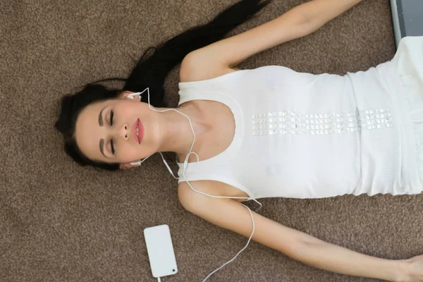 Mujer escuchando música en auriculares en alfombra — Foto de Stock