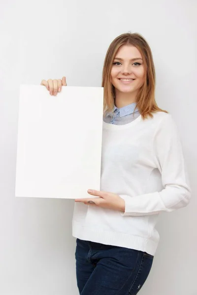 Junge lächelnde Frau zeigt leere Karte oder Papier — Stockfoto