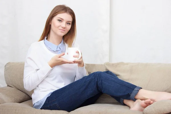 Frau sitzt auf Couch im Wohnzimmer und trinkt Kaffee — Stockfoto