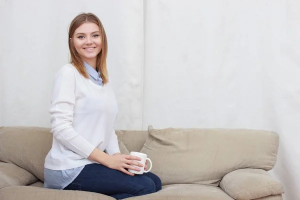 Frau sitzt auf Couch im Wohnzimmer und trinkt Kaffee — Stockfoto