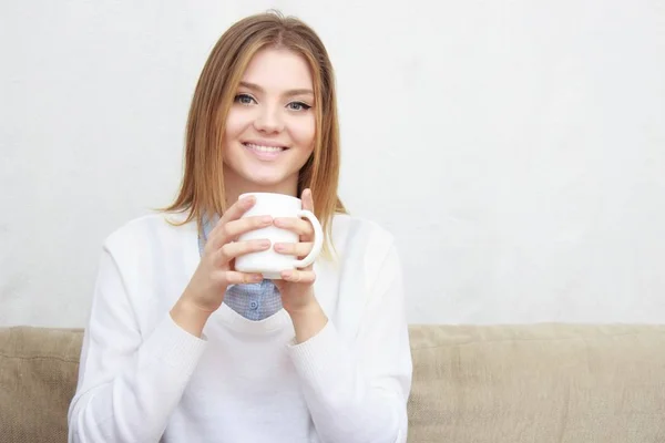 Frau sitzt auf Couch im Wohnzimmer und trinkt Kaffee — Stockfoto