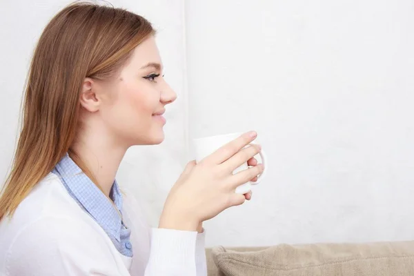 그녀의 거실에 있는 소파에 앉아서 커피를 마시는 여자 — 스톡 사진