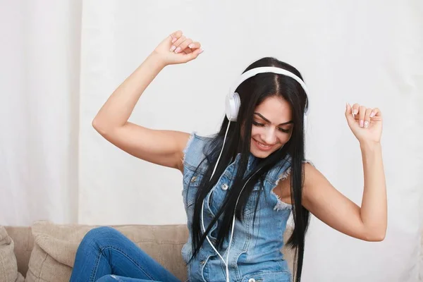 Ein entspanntes Mädchen, das mit Kopfhörern auf dem Sofa sitzt und Musik hört — Stockfoto
