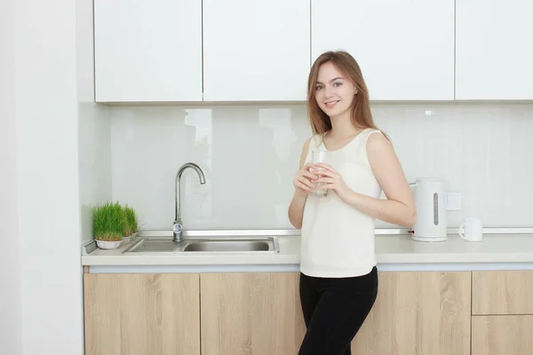 Молодая женщина на кухне пьет воду — стоковое фото