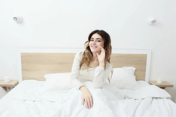 Linda feliz sorrindo jovem mulher sentada na cama — Fotografia de Stock