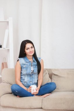 Koyu saçlı kadın onun oturma odasında çay içme.