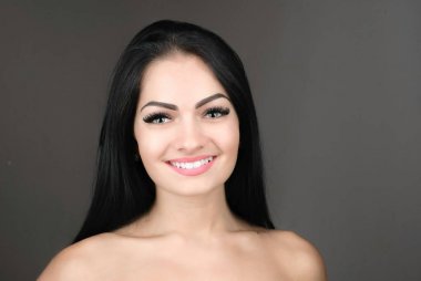 uzun kahverengi saçları gri arka plan üzerinde poz olan genç ve güzel bir kadın