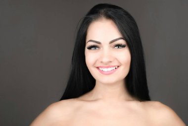 uzun kahverengi saçları gri arka plan üzerinde poz olan genç ve güzel bir kadın