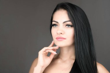 uzun kahverengi saçları gri arka plan üzerinde poz olan genç ve güzel bir kadın