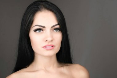 uzun kahverengi saçları gri arka plan üzerinde poz olan genç ve güzel bir kadın