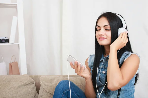 Одна розслаблена дівчина відпочиває і слухає музику з навушниками, сидячи на дивані — стокове фото