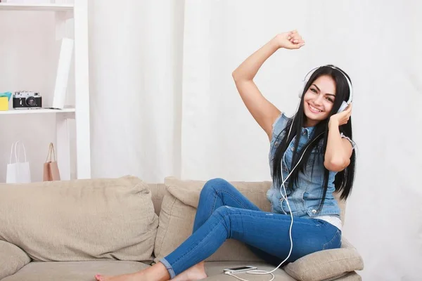 One relaxed girl resting and listening music with headphones sitting on sofa