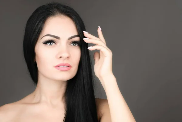 Mulher jovem e bonita com cabelo castanho longo posando sobre fundo cinza — Fotografia de Stock