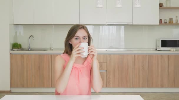 Jonge vrouw drinken thee en glimlachen op camera — Stockvideo