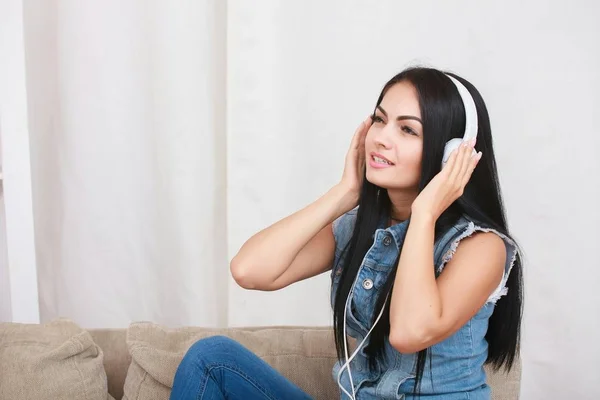 One relaxed girl resting and listening music with headphones sitting on sofa — Stock Photo, Image