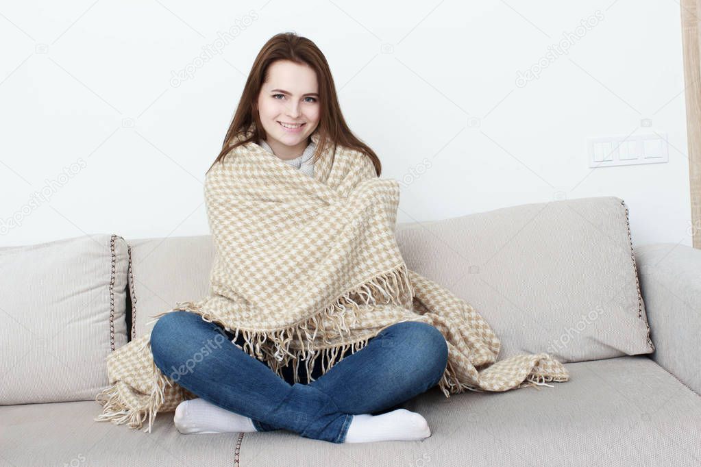 girl is sitting on the sofa under the rug.