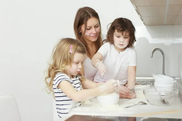Madre con i suoi bambini di 5 anni che cucinano torta di vacanza in cucina — Foto Stock