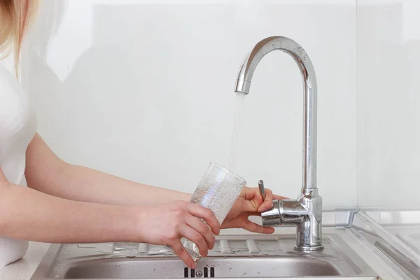 Hermosa joven sostiene un vaso con agua en la cocina — Foto de Stock