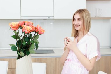 gülümseyen kadın bornoz daimi kahve fincanı evde mutfak ile