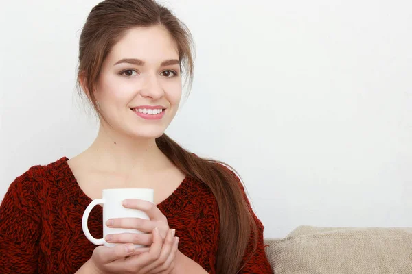 Beautiful young blonde girl in a red sitting on a sofa in a beauty salon — Stock Photo, Image