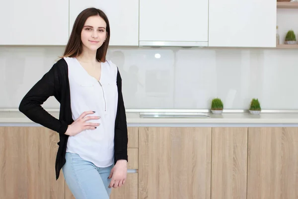 Mulher bonita com cabelo preto em pé na cozinha e sorrindo — Fotografia de Stock